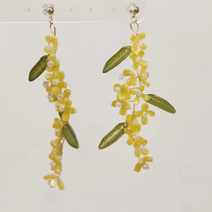 Detailed macro view of handmade long beaded floral drop earrings with green leaves