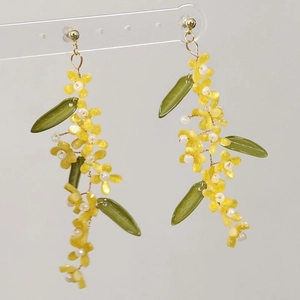 Detail of handmade green leaf and yellow flower tassel earrings with white pearls