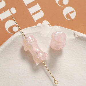 Dettaglio macro di una perla di vetro rosa cangiante a forma di bambù per gioielli