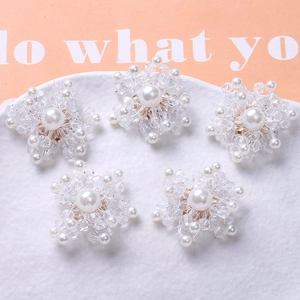 Macro view of five snowflake charms with white pearls and clear faceted beads