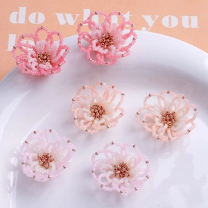 Makro-Detail von handgefertigten Perlenblumen in Rosa und Weiß für DIY-Schmuckherstellung