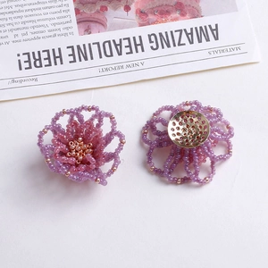 Detailansicht handgefertigter lila Perlenohrringe in Blumenform mit goldenen Akzenten und Basis