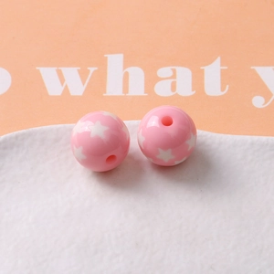 Macro view of 16mm pink resin beads with white star patterns for DIY jewelry making