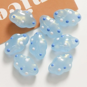 Primer plano de cuentas en forma de nube azul claro translúcido con lunares blancos