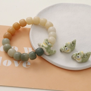 Detail of green dinosaur ceramic charm with gradient beaded bracelet for DIY jewelry