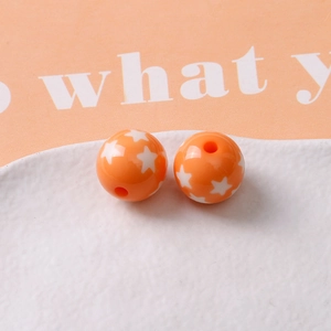 Macro shot of two orange resin star beads with through holes for DIY jewelry making