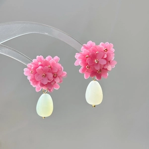 Detail showing layered pink flower petals with golden center and white teardrop bead