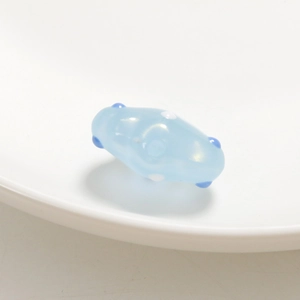 Primer plano de cuenta de vidrio azul claro con puntos blancos y azules para bisutería
