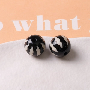 Detailed close-up of 16mm black resin pumpkin beads with white stripes for DIY jewelry