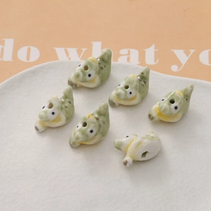 Detail view of small ceramic crocodile beads in light green and yellow for DIY jewelry