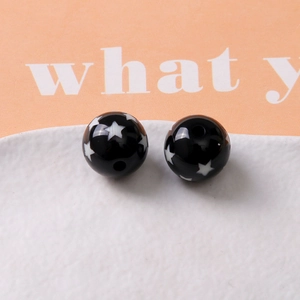 Close-up of black resin round beads with white star pattern and center hole for DIY jewelry