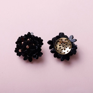 Detail of handmade flower earrings with black sequins and golden metal filigree base