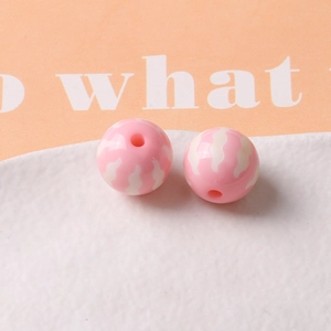 Macro shot of pink pumpkin-shaped resin beads with white wavy texture for DIY jewelry making