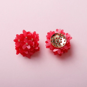 Detailed macro view of handmade red five-petal flower charms with golden metal base