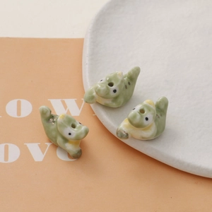 Macro shot of three light green ceramic crocodile beads with polished glaze for DIY jewelry