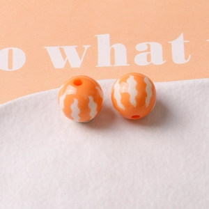 Macro shot of 16mm orange pumpkin resin beads with white wavy stripes for DIY jewelry making