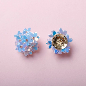 Macro view of iridescent blue woven flower charm with a golden metallic base back