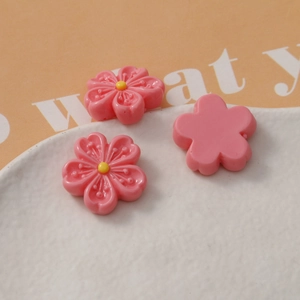 Detailed close-up of pink resin cherry blossom charms for DIY crafts and accessories