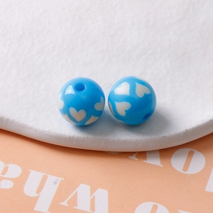 Vue macro de perles en résine bleue 16mm avec motifs de cœurs blancs pour bijoux DIY