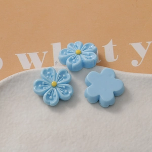 Macro shot of blue resin five-petal cherry blossom DIY charms with yellow centers