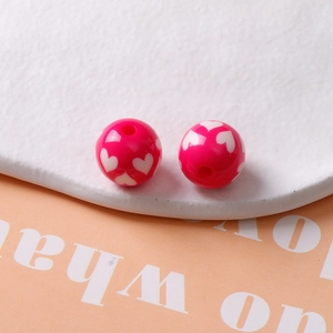 Vue macro de perles en résine rouge rose 16mm avec motifs de cœurs blancs pour bijoux