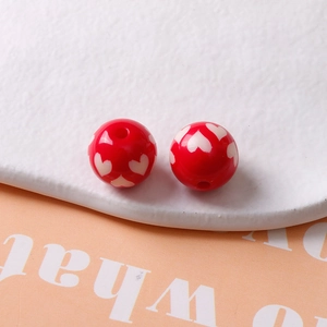 Vue macro de perles en résine rouge de 16mm avec motifs de cœur blanc pour bijoux DIY