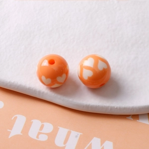 Détail de perles de 16mm en résine orange avec motif de cœur et trou vertical pour DIY