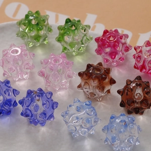 Macro view of colorful translucent hedgehog beads for jewelry making on white tray