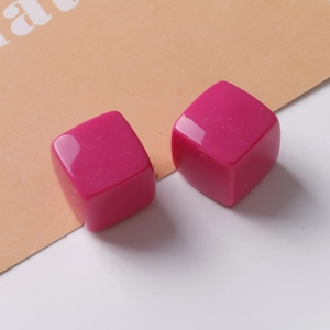 Macro detail of 20mm magenta resin cube charms with a glossy finish for DIY jewelry