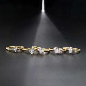 Detailed view of five gold rings with various zircon shapes on a dark background