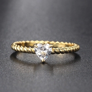 Detail of twisted gold ring band featuring a heart-shaped zircon in a three-prong setting