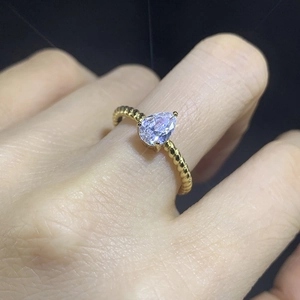 Detail showing a pear-cut zircon on a golden twisted rope band worn on a finger