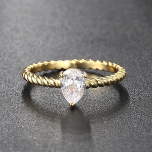 Detail of pear-cut zircon ring with twisted rope gold band on a dark textured background