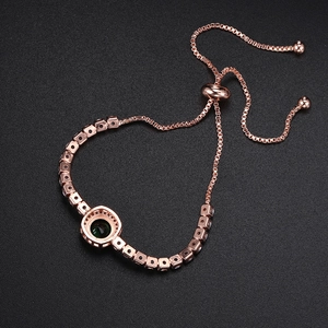 Detail of rose gold bolo bracelet with green round center stone and square zircons