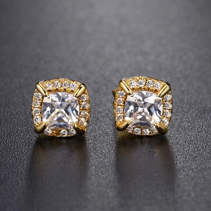 Macro shot of gold square halo earrings with cushion-cut zircon on black texture