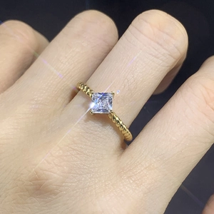 Close-up of golden twisted rope ring featuring a square princess cut cubic zirconia