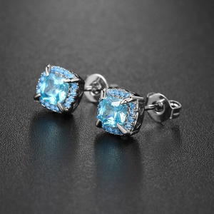 Macro shot of square-cut sky blue gemstone halo stud earrings with silver metal backings