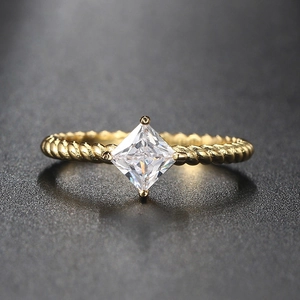 Macro detail of gold twisted band ring with a square-cut sparkling white zircon stone