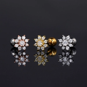 Detalle de pendientes de flor con circón en oro rosa, oro y plata con cierre de bola