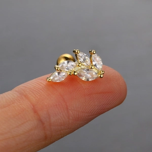 Makroaufnahme von blattförmigem Goldohrstecker mit Zirkonia-Steinen auf einer Fingerspitze