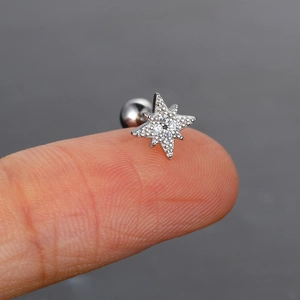 Vista macro de un piercing de estrella de ocho puntas en plata y circonitas sobre un dedo