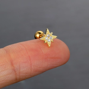 Vista detallada de un piercing estrella del norte dorado con piedras de circón