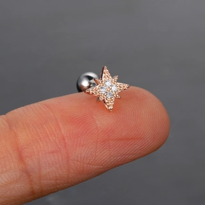 Detalle de un pequeño pendiente de estrella en oro rosa con circonitas sobre la yema del dedo