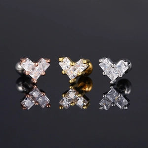 Detalle macro de pendientes de circonita con forma de corazón en oro, rosa y plata