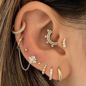 Macro shot of gold-plated stud earrings with clear zircon stones on a model's ear
