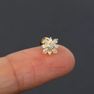 Macro detail of a golden flower screw back stud earring with marquise and round zircons