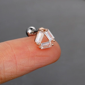 Primer plano de un pendiente de circonita con cristal triangular en la punta del dedo