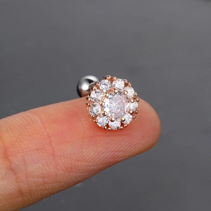 Detalle macro del pendiente de flor en oro rosa con circón y cierre de rosca