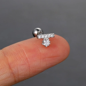 Vista macro de un pequeño piercing de oreja con estrellas y circonitas sobre la punta del dedo