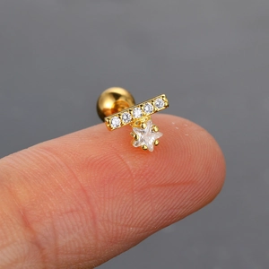 Detalle de un mini pendiente de estrella dorada con circón en la punta del dedo